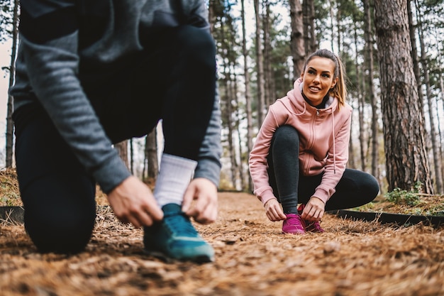 Paar koppelverkoop schoenveter en voorbereiding voor lange termijn in het bos in de herfst. Selectieve aandacht bij vrouw.