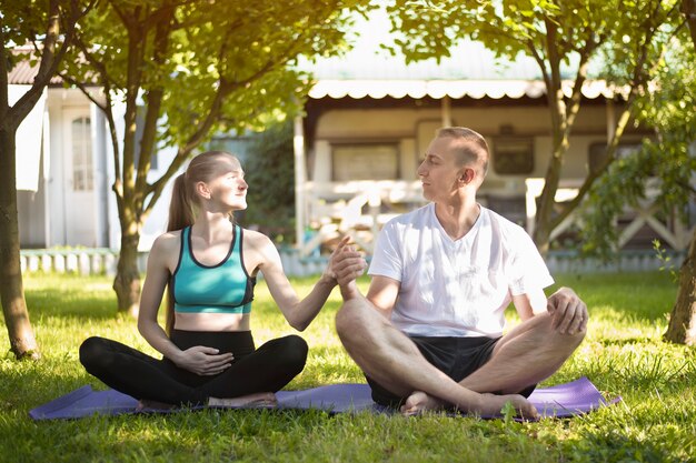 Paar liefhebbers die yoga in de tuin beoefenen. Zwangere vrouw. Zomerochtend