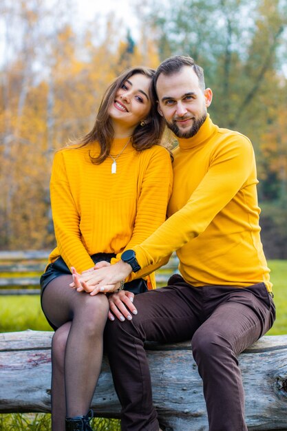 Paar liefhebbers gekleed in gele coltruien in het park knuffelen