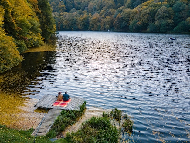Paar liggend op de pier aan het meer bedekt met herfstbladeren