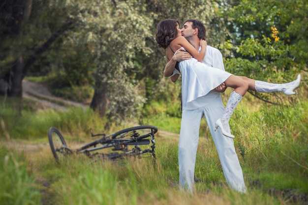 Paar man en vrouw in bruiloft stijl met fietsen in de natuur gelukkig