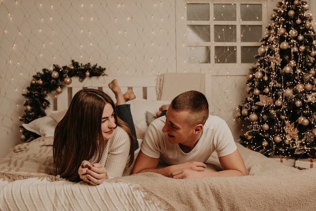 Paar man en vrouw liggen op bed slaapkamer kerstboom