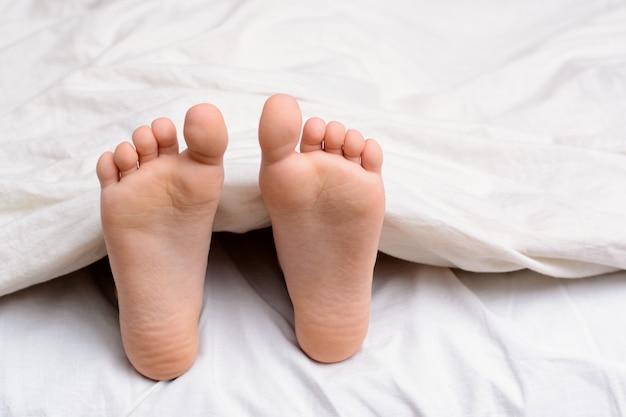 Paar meisje` s voeten in een bed