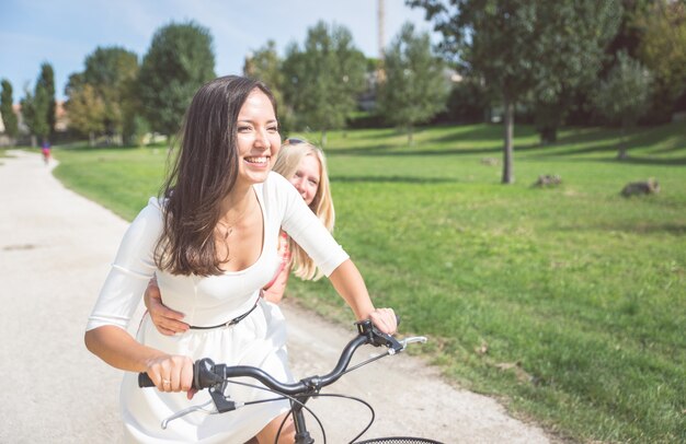 Paar meisjes rijden met fiets in het park