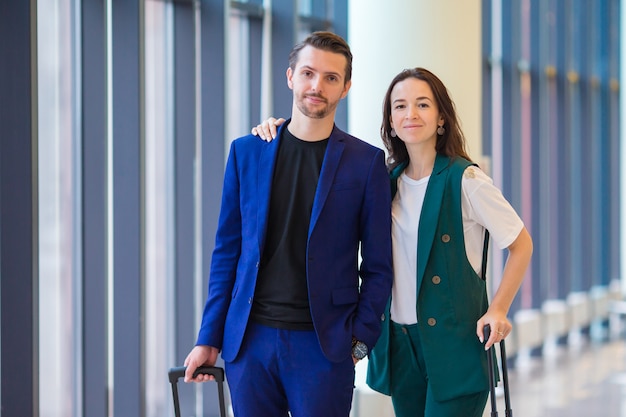 Paar met bagage in internationale luchthaven die zich voor een vlucht haasten om te landen. Man en vrouw die op hun klok binnen dichtbijgelegen groot venster kijken