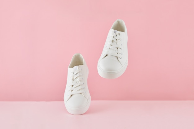 Paar mode stijlvolle witte sneakers, sportschoenen uitgevoerd op een pastel roze achtergrond.