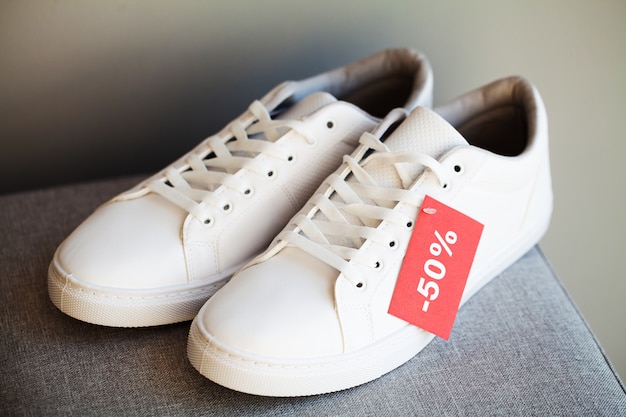 Paar nieuwe stijlvolle witte sneakers met korting op grijs