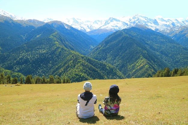 Paar ontspannen op de weide van Highland Admiring View of Caucasus Mountain, Mestia, Georgia