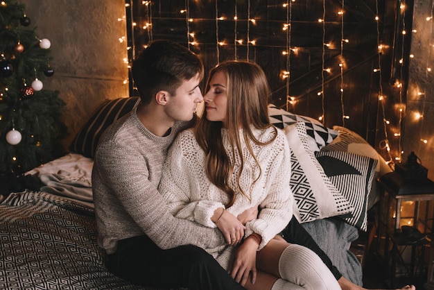 Paar op het bed in de slaapkamer donker interieur nieuwjaar en kerst knuffels en kusjes hou van witte zw...