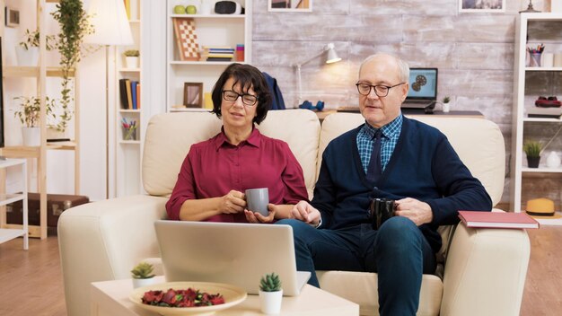 Paar oude mensen die moderne technologie gebruiken. Ze voeren een videogesprek met een laptop