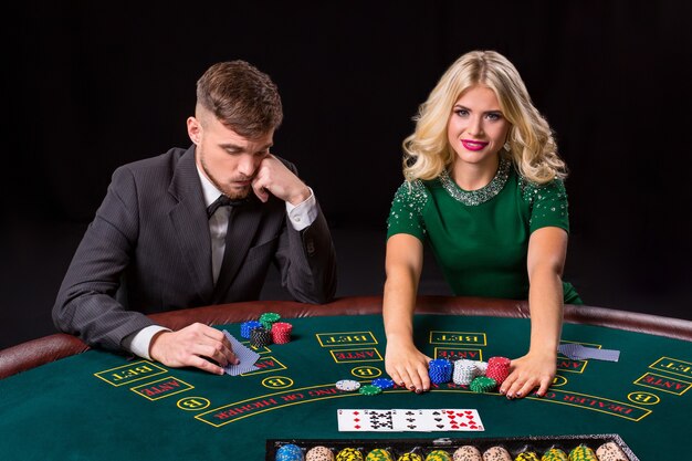 Paar pokeren aan de groene tafel. Het blonde meisje en een man in een pak. all-in inzet chips