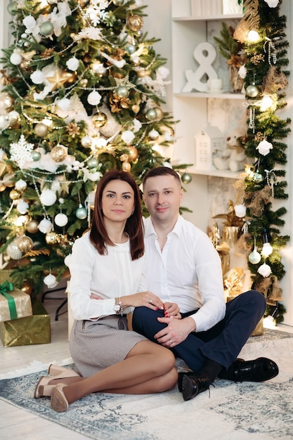 Paar poseren naast kerstboom