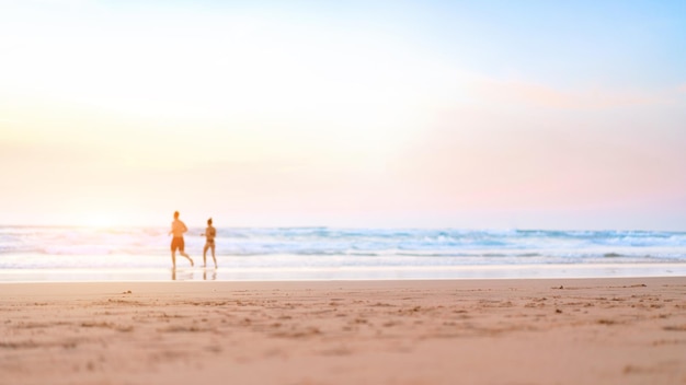 Paar rennen op het strand Gelukkig paar gaan zwemmen in de oceaan bij zonsondergang