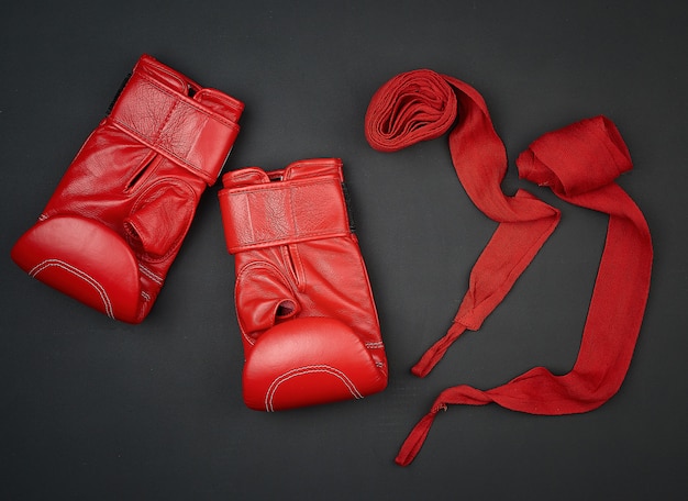 Paar rode lederen bokshandschoenen en rood textielverband op een zwarte