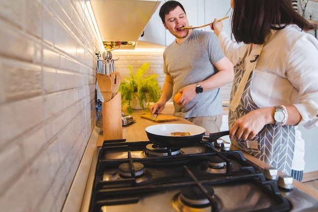 Paar samen koken in de keuken, pannenkoeken bakken en sinaasappelsmakend eten snijden