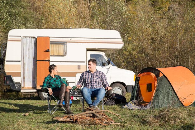 Paar samen ontspannen op een camping na een avontuur in de bergen. Kamperen met retro camper.