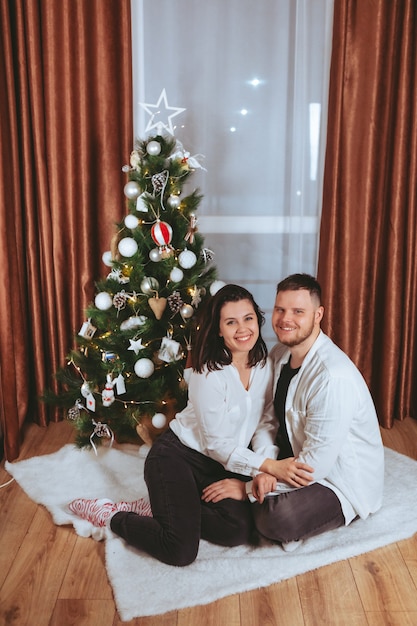 Paar schieten voor versierde kerstboom kopieer ruimte cadeaubon
