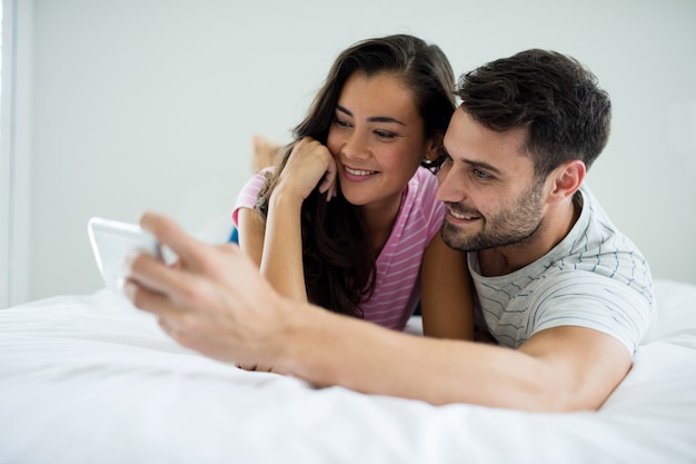 Paar selfie te nemen vanaf mobiele telefoon in de slaapkamer thuis