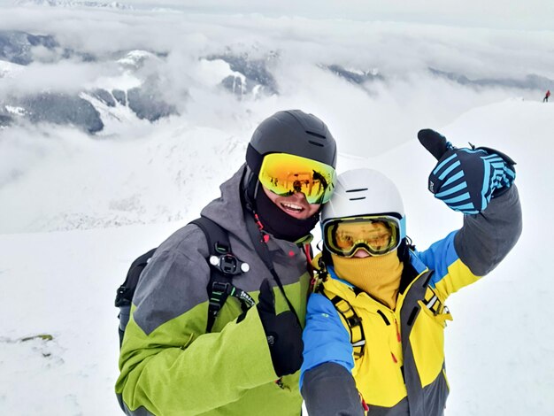 Paar skiër en snowboarder selfie nemen op de bergtop