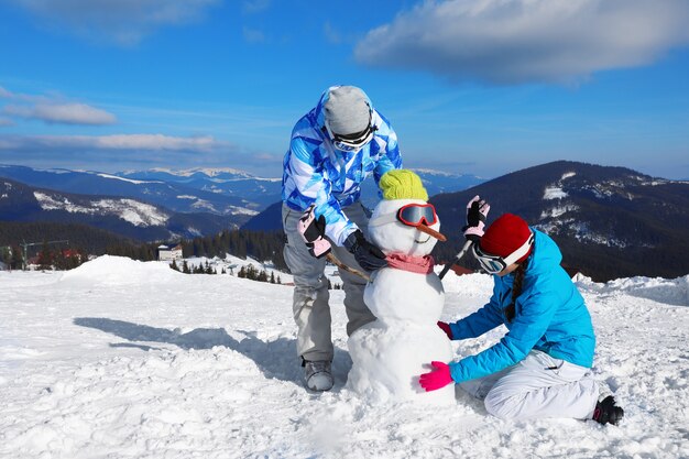 Paar sneeuwpop maken in skigebied. Winter vakantie