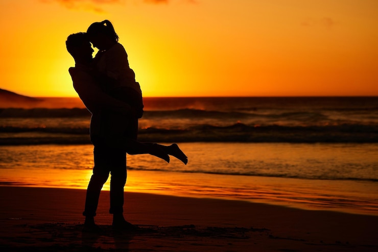 Foto paar strand en zonsondergang met een man en vrouw knuffelen aan de kust met een gouden uitzicht op de achtergrond liefde silhouet en oceaan met een man en vrouw omhelzen op het zand aan zee voor reizen