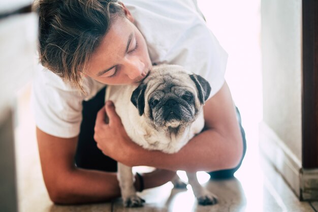 Paar tiener en schattige witte mopshond - liefde en genegenheid van twee beste gebraden thuis - houden van de dieren