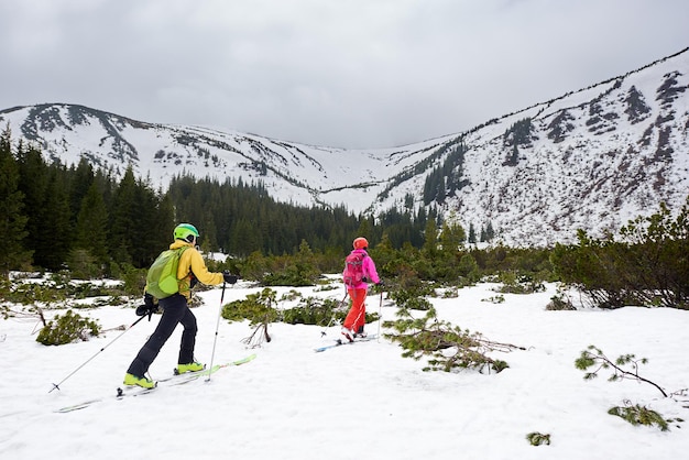 Paar touring skiërs backpackers lopen op ski's naar besneeuwde berg Achteraanzicht Winter recreatie tijdverdrijf samen