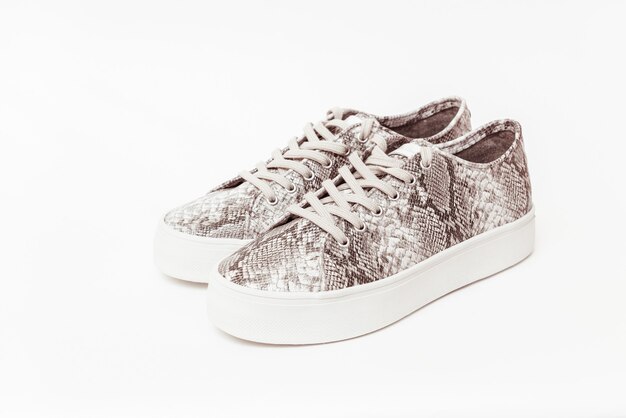 Paar trendy sneakers op lichte muur, plat leggen