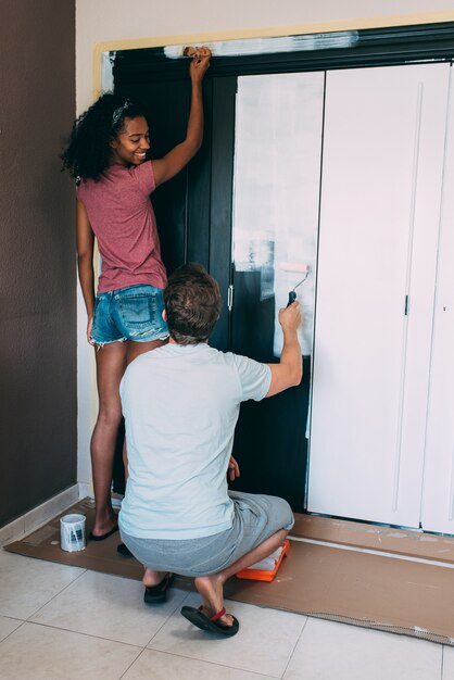 Paar tussen verschillende rassen die een garderobe schilderen