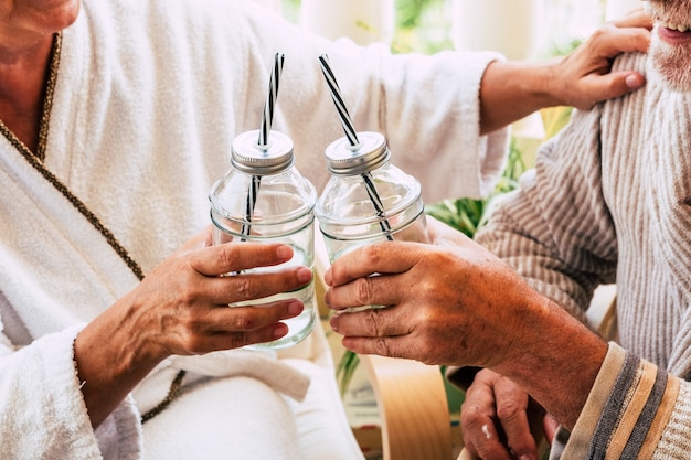 Paar twee senioren of volwassen mensen die samen thuis of in een hotel een drankje of cocktail drinken tijdens een massagebehandeling