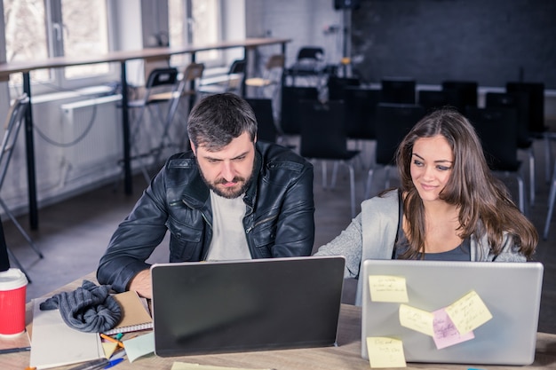 Paar universiteitsstudenten studeren samen met laptops in collegezaal