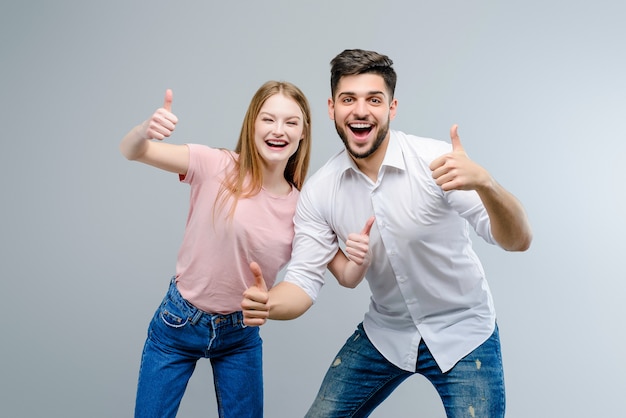 Paar van jonge man en vrouw die omhoog geïsoleerde duimen tonen