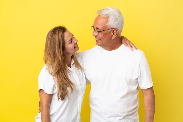 Paar van middelbare leeftijd geïsoleerd op gele achtergrond gelukkig en lachend