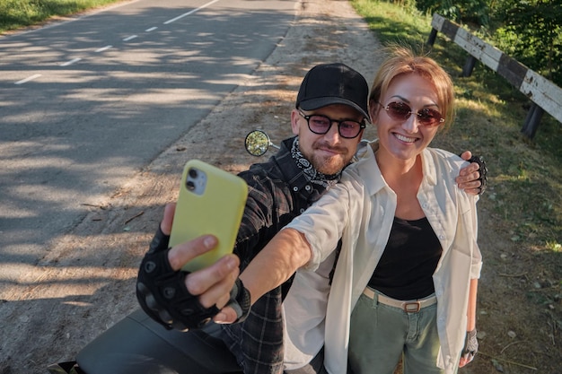 Paar van middelbare leeftijd op een motorfiets die plezier heeft en een selfie maakt op de camera van een mobiele telefoon