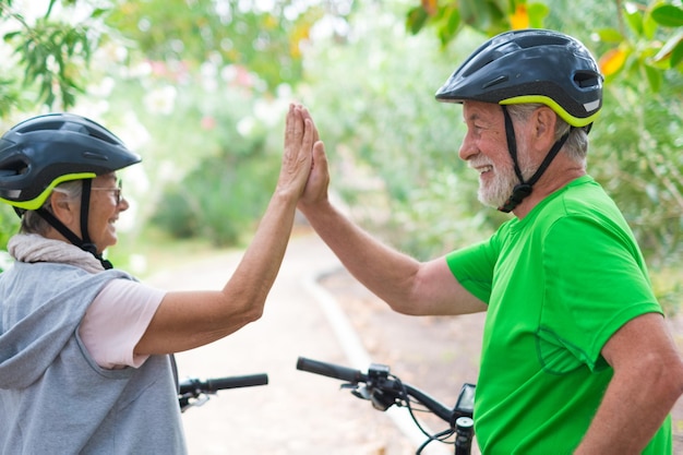 Paar van twee senioren die samen vijf geven buiten plezier maken met fietsen genieten van de natuur Paar ouderen die een gezonde en fit levensstijl bouwenlexA