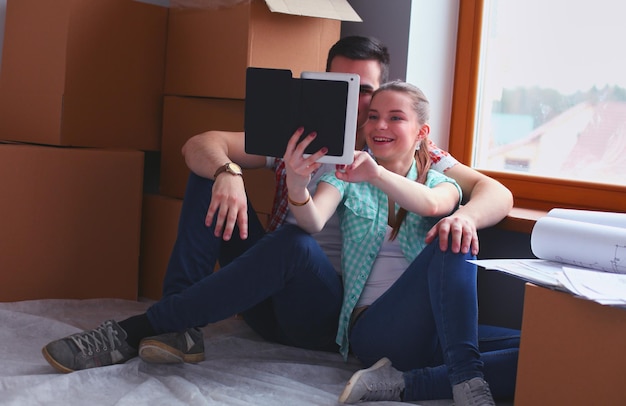 Foto paar verhuizen in huis zittend op de vloer met ipad couple