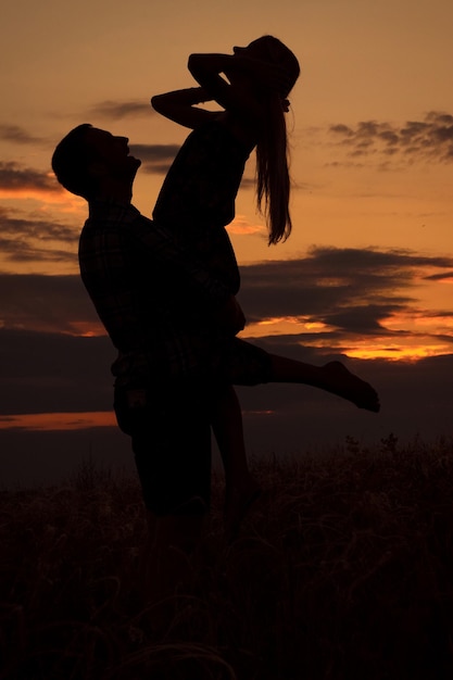 Paar verliefd blond meisje in silhouet tegen een zonsondergang