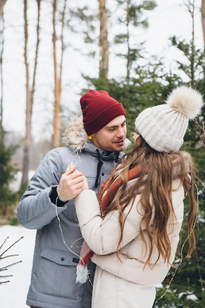 Paar verliefd knuffels en kusjes in een winter naaldbos