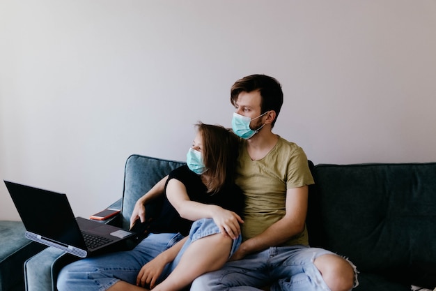 paar verliefd op medische isolatie in medische maskers zitten op de bank