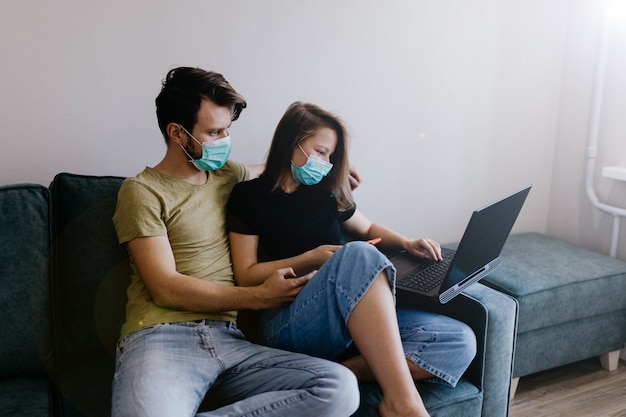 paar verliefd op medische isolatie in medische maskers zitten op de bank