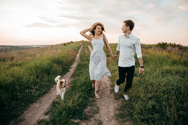 Paar verliefd wandelen met hond op de heuvels hand in hand