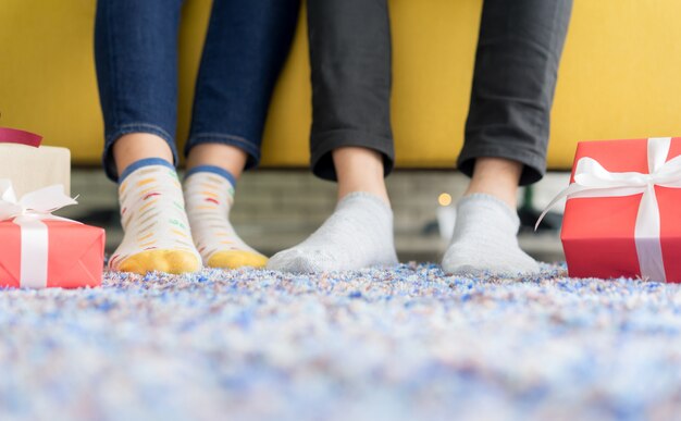 paar voeten met sokken en geschenkdozen en zittend op tapijt