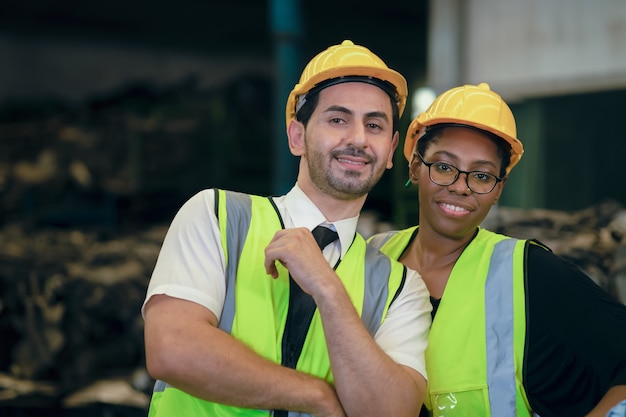 Paar vriend Team Worker mix race geniet van het werken in een zware fabriek die samen staat, gelukkig lachend portret shot op zoek naar camera