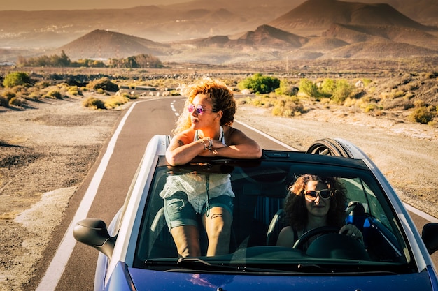 Paar vrienden volwassen vrouwen die samen gratis en onafhankelijk reizen in een cabriolet met mountsins en wilde natuurwoestijn in scene