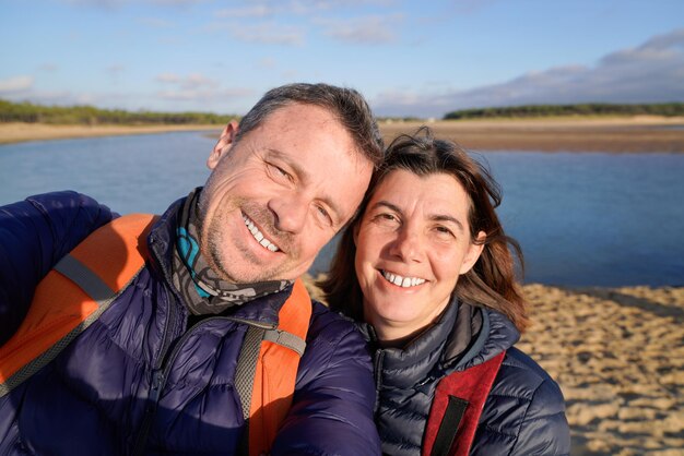 Paar vrouw en man gelukkig nemen selfie telefoon zelfportret met smartphone camera met plezier op strand kust zand oceaan