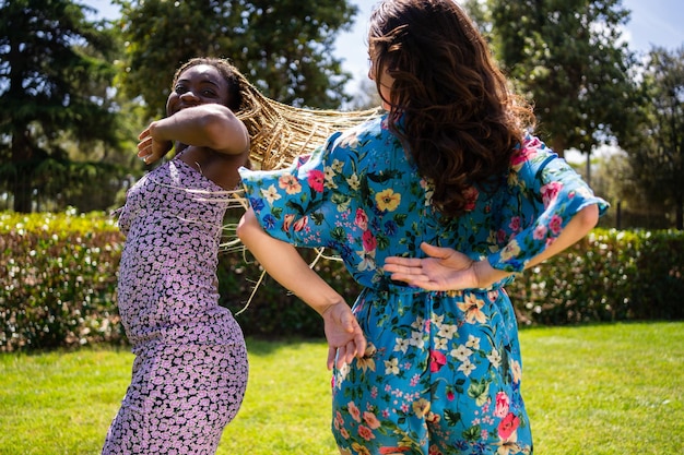 Paar vrouwen van verschillende etniciteiten die energiek dansen in een tuin