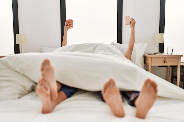 Paar wakker onder deken Ontbijten met kopje koffie omhoog op het bed