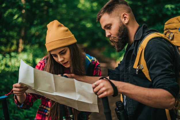 Paar wandelaars die trekkingstokken en kaart gebruiken terwijl ze de dag in de natuur doorbrengen