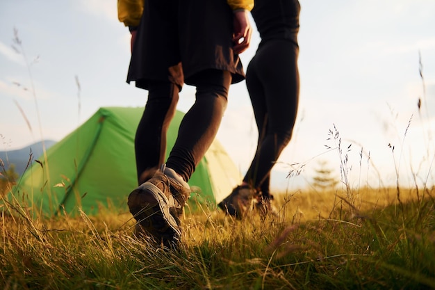 Paar wandelen buiten in de buurt van groene tent Conceptie van reizen