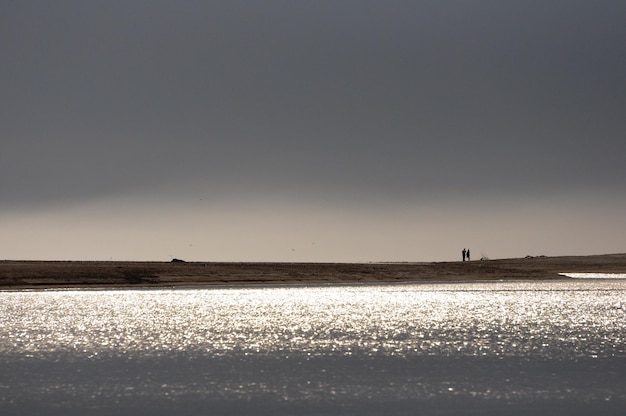 Paar wandelen op het strand tijdens zonsondergang in de buurt van een rivier in Maldonado, Uruguay